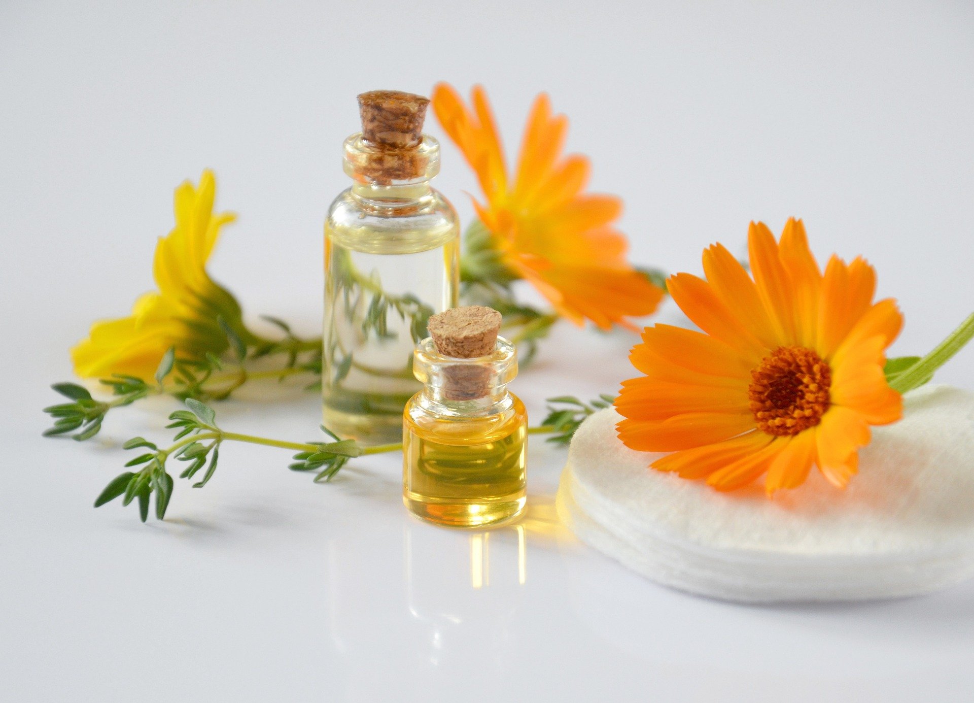essential-oils-ge624ddb35_1920.jpg Zwei kleine Fläschchen mit Ölen, umgeben von gelben Blüten und einem Wattepad.