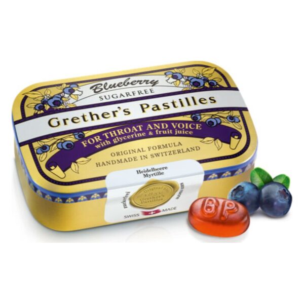 Blaubeerpastillen von Grether in einer goldenen Dose mit Aufschrift für Hals und Stimme, neben einer Blaubeere und einer Pastille.